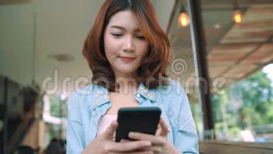 快乐的亚洲年轻女人坐在咖啡馆里，用智能手机聊天、阅读和发短信。 妇女生活方式概念